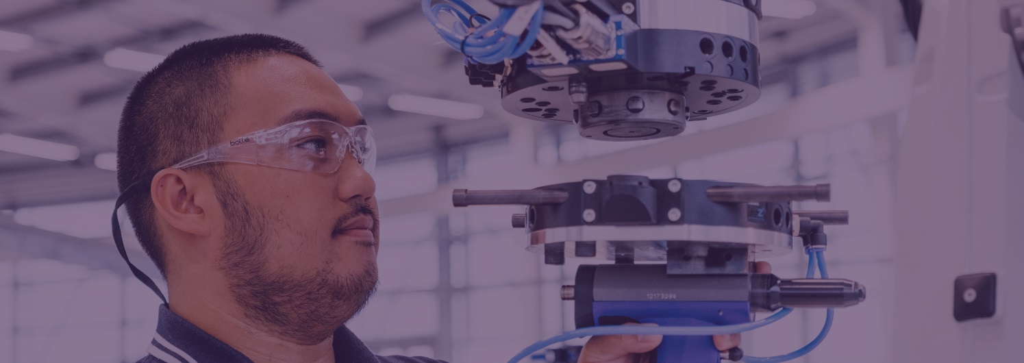 Factory worker inspecting machine with safety goggles on